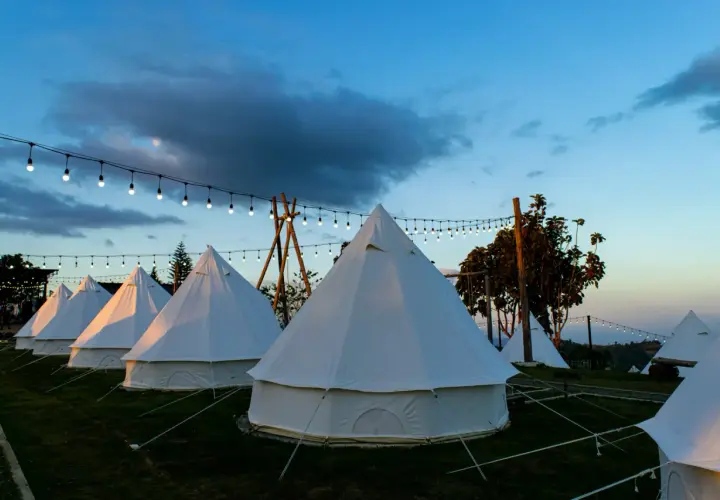 Nocleg w namiotach typu dzwon, oświetlonych girlandami. To właśnie glamping co to – luksusowy kemping w otoczeniu natury.