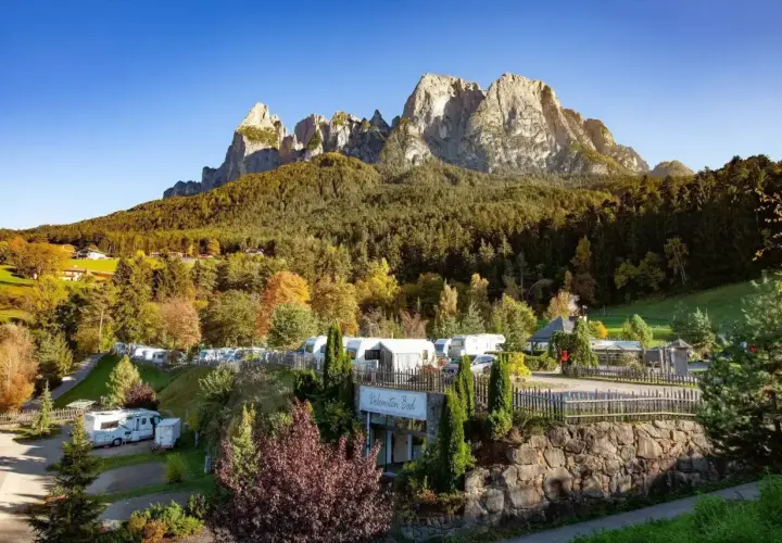 Malowniczy camping Seiser Alm z kamperami i przyczepami pod majestatycznymi szczytami Dolomitów.