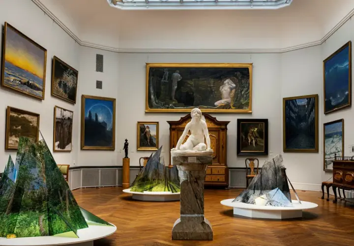 Konsthall med målningar och skulpturer. I förgrunden syns moderna installationer som speglar naturen. Thielska museet bjuder på en fascinerande blandning av gammalt och nytt.