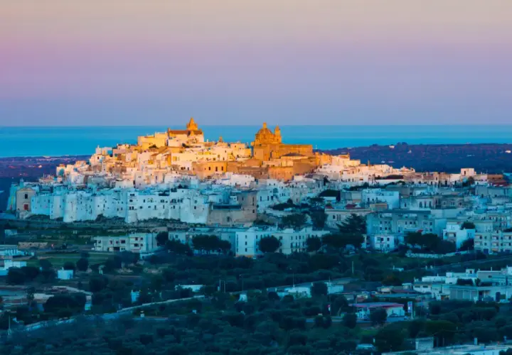 Ostuni, the "White City," glows at sunset, a beautiful destination near the closest airport to Puglia, Italy.