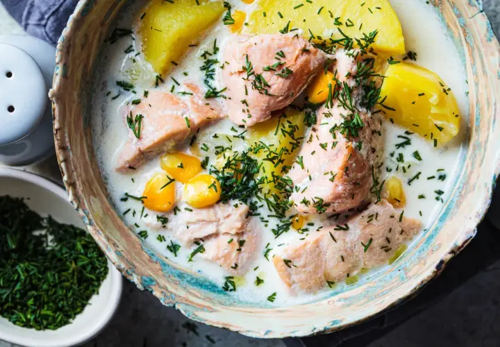 Łosoś w śmietanowym sosie z ziemniakami i kukurydzą, posypany koperkiem. Danie wygląda apetycznie, choć norwegia ceny w restauracjach mogą być wysokie.