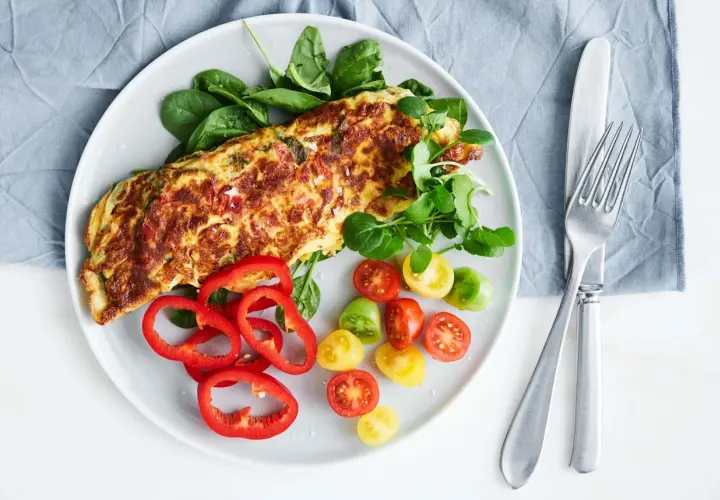 En gyllene, nyttig omelett serverad med färska grönsaker som spenat, körsbärstomater och paprika. En perfekt start på dagen!