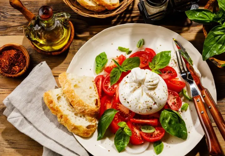 Pyszny ser burrata z pomidorami i bazylią, podany z chrupiącym pieczywem. Idealny na letni obiad.