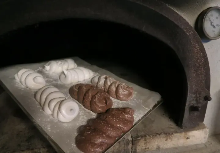 Des meringues blanches et chocolatées sont en cours de cuisson dans un four rustique.