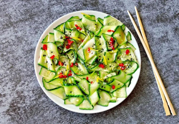 Insalata di cetrioli affettati sottili, condita con peperoncino, sesamo e scorza di limone. Un'idea fresca per le tue ricette con cetrioli.