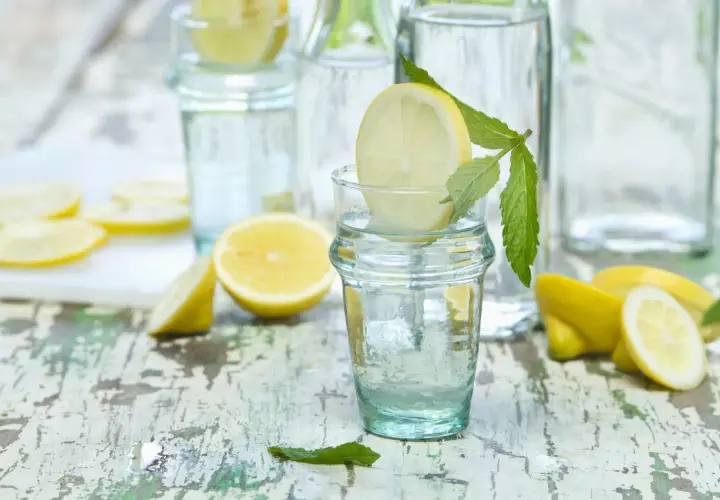Agua con limón y menta en vasos, ideal para refrescar y para que es bueno el agua con limon: digestión y vitalidad.