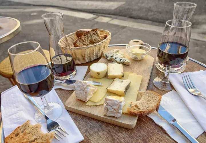 Un plateau de fromages variés, du pain et du vin rouge, une scène qui raconte une belle histoire de la cuisine française.