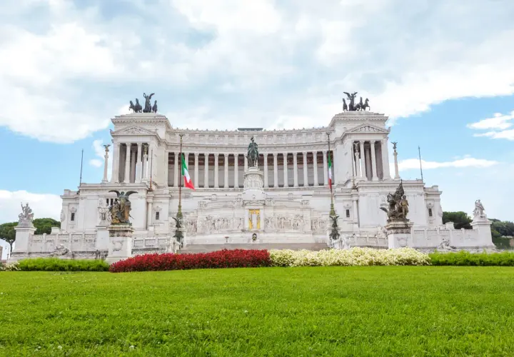 Imponente altare della patria statua equestre al centro, circondato da colonne, bandiere italiane e sculture.