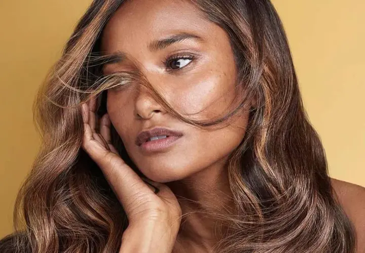 Mujer con cabello largo y ondulado con un tinte color miel o caramelo, con mechones más claros que resaltan su rostro.