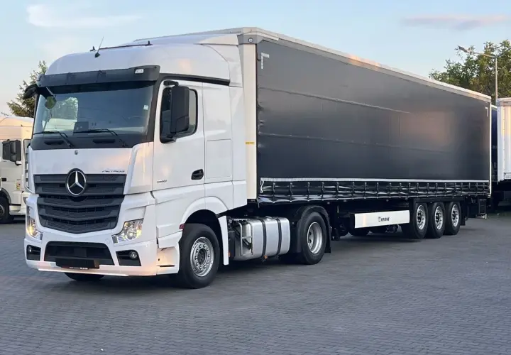 Biały Mercedes Actros MP4 z czarną plandeką naczepy Krone, gotowy do trasy.