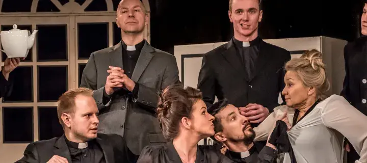 Na scenie Teatru Capitol rozgrywa się intryga. Aktorka w stroju pokojówki trzyma dzbanek, a wokół niej zgromadzeni mężczyźni w sutannach i jeden w stroju lokaja.