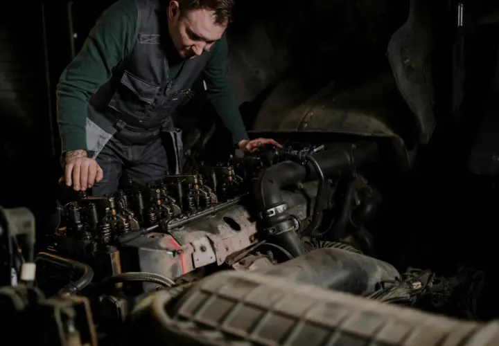 Mechanik w kamizelce pracuje nad silnikiem, wykonując odpowietrzanie silnika.