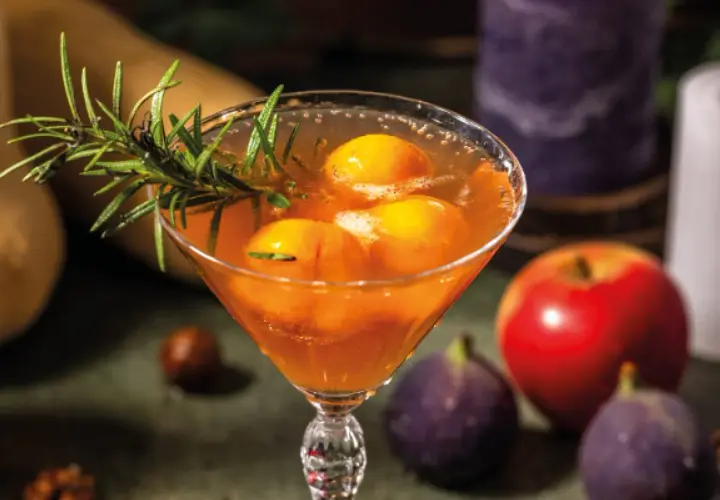 Cocktail fruité avec des pêches et du romarin, parfait pour une idée apéro mariage. Pomme et figues en arrière-plan.