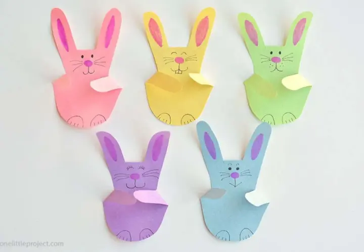 Fünf bunte Papierhasen, jeder ein einfacher hase, sitzen nebeneinander.