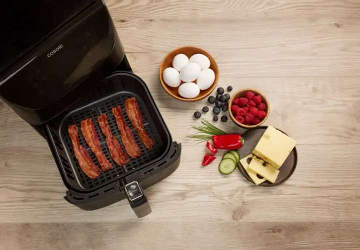 Krispigt bacon i airfryer, redo för en god frukost med ägg, bär och ost.