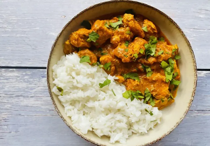 Aksamitny kurczak tikka masala w kremowym sosie, podany z puszystym ryżem i posypany świeżą kolendrą.