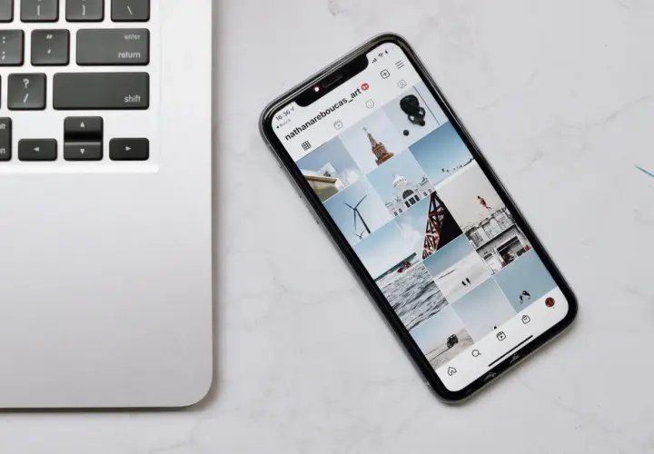 Telefon z Instagramem obok klawiatury laptopa. Dowiedz się, jak połączyć telefon z komputerem przez wifi, by łatwo przesyłać zdjęcia.