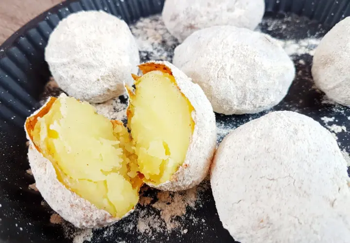 Pyszne ziemniaki z ogniska, upieczone w popiele, jeden przekrojony na pół, ukazujący miękki, żółty środek.