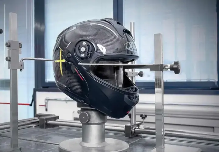 Casco in prova su banco per capire se un casco è omologato. Strumenti di misurazione puntano il guscio in carbonio.