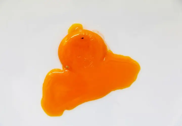 Un œuf rouge, éclatant sur une surface blanche, sa texture liquide et vibrante évoque une œuvre d'art abstraite.