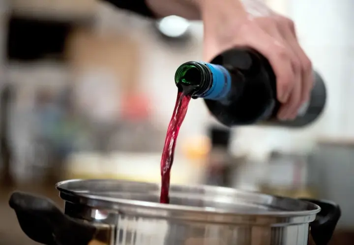 Rotwein wird in einen Topf gegossen. Beim Kochen verdunstet Alkohol.