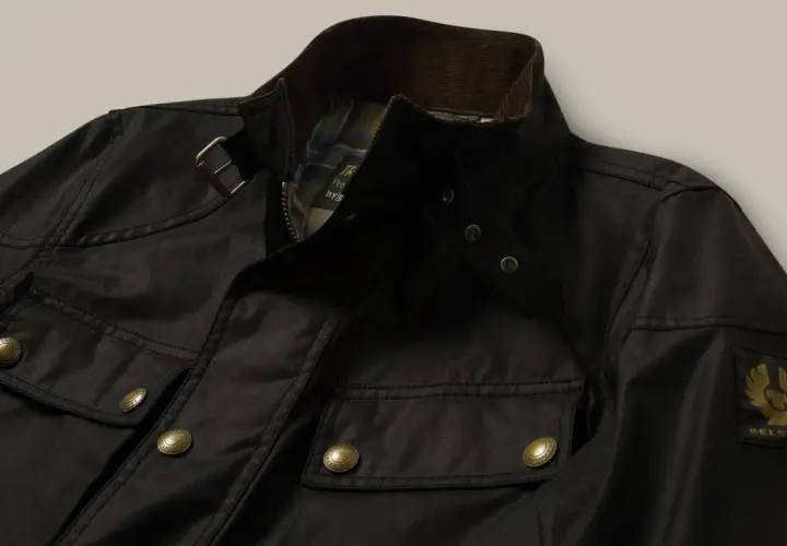 Chaqueta Belstaff negra, lista para limpiar en casa. Detalles de bolsillos, cremallera y logo dorado.