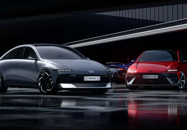 Dwa modele Hyundai Ioniq 6, jeden szary, drugi czerwony, stoją na mokrej nawierzchni w nowoczesnym wnętrzu.
