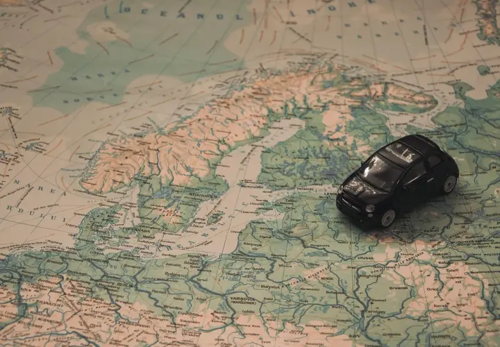 Une petite voiture noire sur une carte d'Europe. Idéal pour une musique à mettre dans sa playlist de road trip.