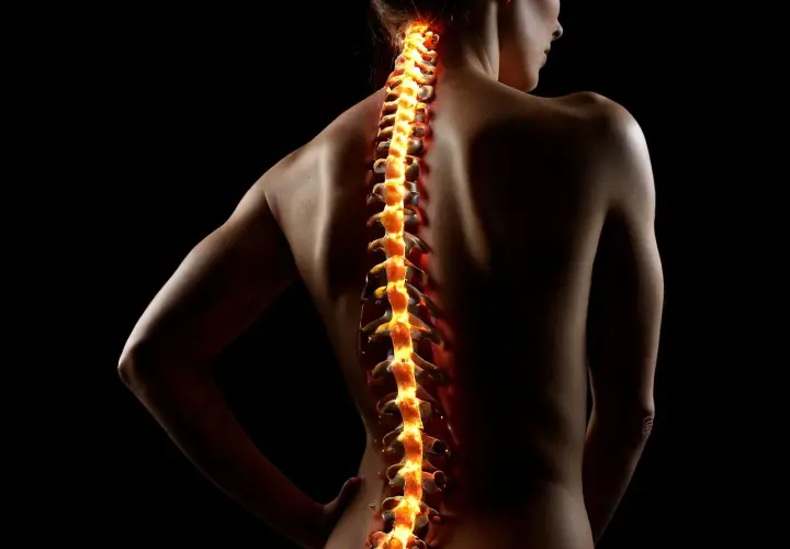 Płonący kręgosłup kobiety, symbolizujący bóle i potrzebę diagnostyki w kinezyterapii i masażu.