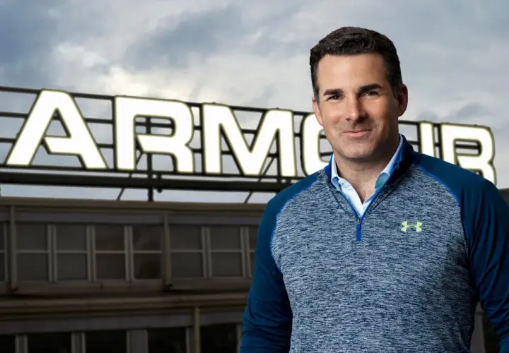 Mężczyzna w bluzie Under Armour na tle budynku z napisem ARMOUR.
