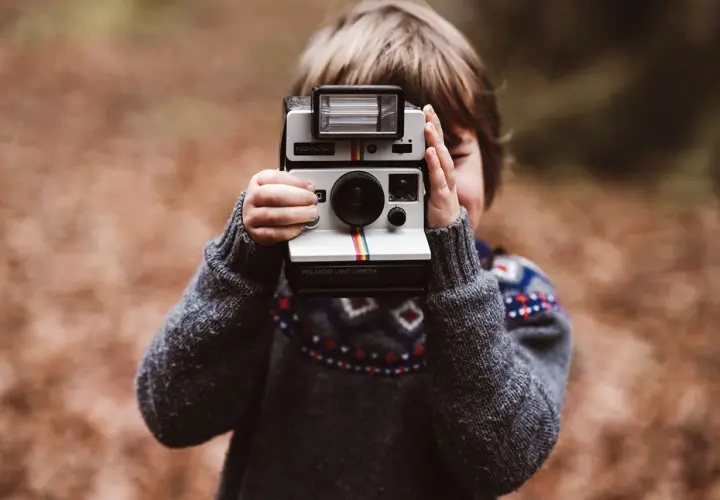 Dziecko z aparatem Polaroid Land Camera, gotowe do uchwycenia magicznych chwil.