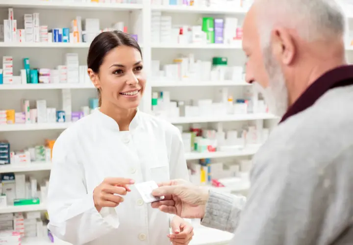 Farmaceutka podaje starszemu panu opakowanie leku, sugerując eliquis zamiennik.