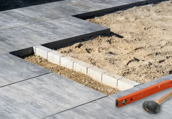Budowa tarasu: układanie płyt betonowych, obrzeża i narzędzia budowlane.