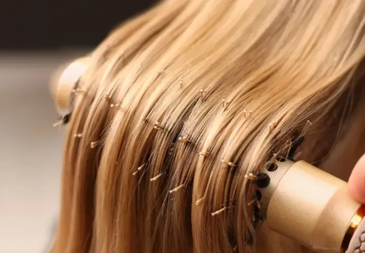 Delikatne rozczesywanie blond pasm przedłużanych włosów okrągłą szczotką. Poznaj sekrety, jak dbać o przedłużane włosy, by były lśniące i zdrowe.