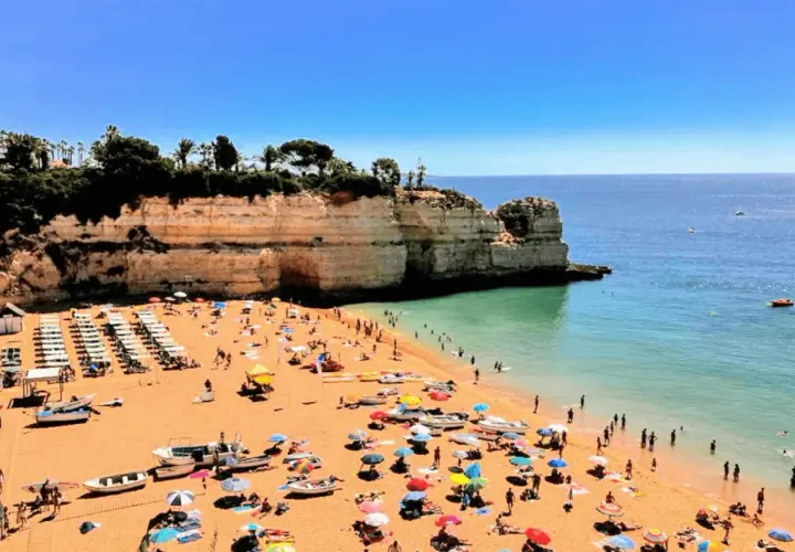 Playa con gente disfrutando del sol y el mar. Un día perfecto para actividades en el Algarve.