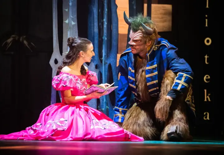Piękna Bella w różowej sukni czyta Bestii z poznańskiego Teatru Muzycznego. Sprawdź repertuar!