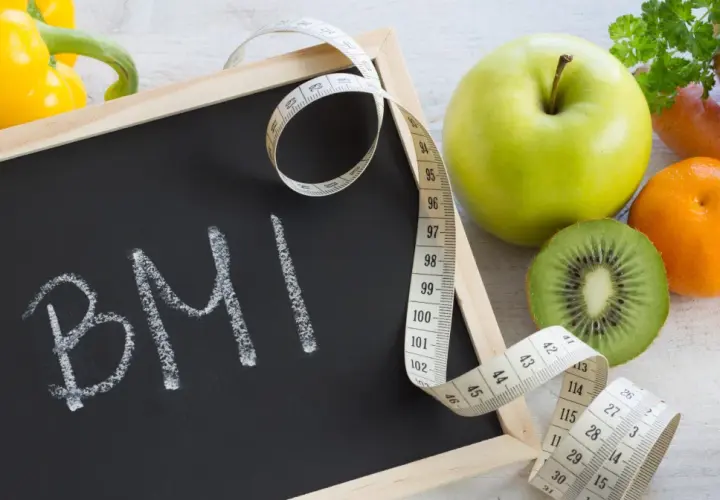 Tablica z napisem BMI, miarka krawiecka i świeże owoce. Zastanawiasz się, ile powinnaś ważyć w ciąży?