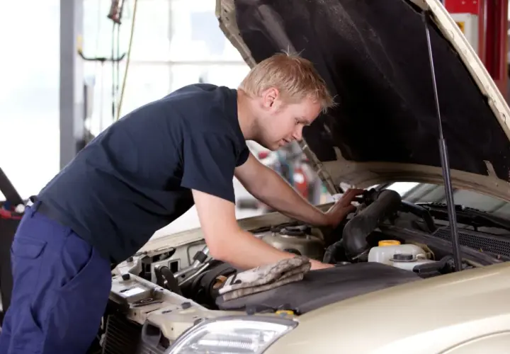 Mężczyzna pracuje przy silniku samochodu, ucząc się na kursie mechanika samochodowego dla dorosłych.