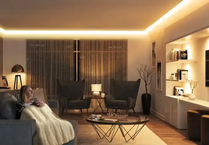 Mujer relajada en sofá con manta, rodeada de cálida iluminación ambiental de 3000k color.