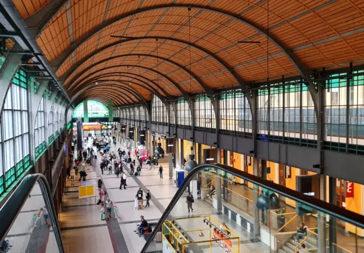 Wrocław jak dojechać z dworca na rynek? Wnętrze dworca z łukowym dachem, ludźmi i schodami ruchomymi.