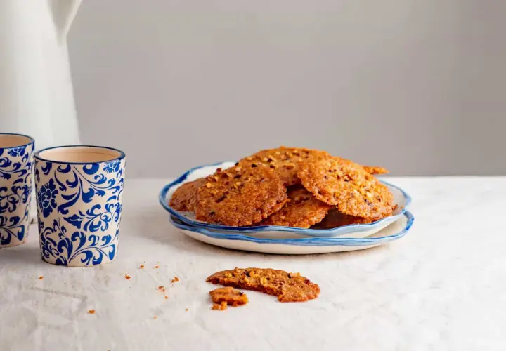 Deliciosas galletas de jengibre crujientes con trozos de nueces, servidas en un plato azul y blanco.