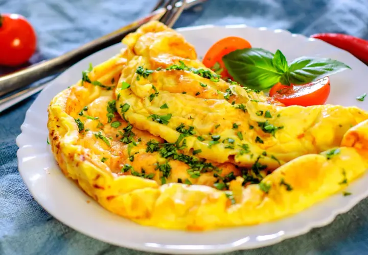 Une omelette dorée et moelleuse, garnie de persil frais. Une recette simple et rapide pour un repas savoureux.
