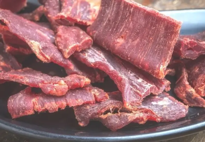 Suszone plastry mięsa wołowego na czarnym talerzu. Idealne do przekąski, gdy szukasz prostego beef jerky przepis.