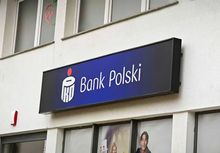 Logo Banku Polskiego na niebieskim tle. Obok widoczny czerwony sygnalizator. W tle okna z grafikami, być może ankieta AML.