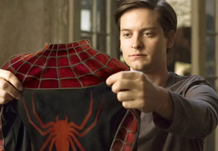 Tobey Maguire examine le costume de Spider-Man, un moment clé dans les films avec Tobey Maguire.