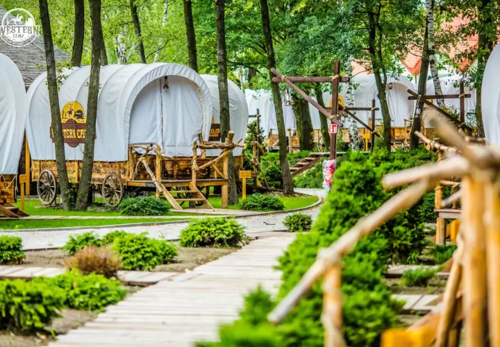 Wagony kempingowe w stylu western, idealne na wyjazd gdzie z dzieckiem w Krakowie. Drewniane ścieżki i bujna zieleń tworzą magiczny klimat.
