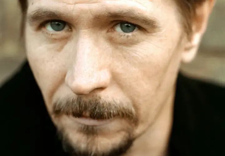 Młody Gary Oldman z przenikliwym spojrzeniem i charakterystycznym wąsikiem.