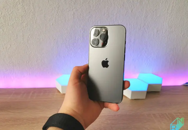 Dłoń trzyma szary iPhone 13 Pro z potrójnym aparatem. Wymiary telefonu idealnie pasują do dłoni.