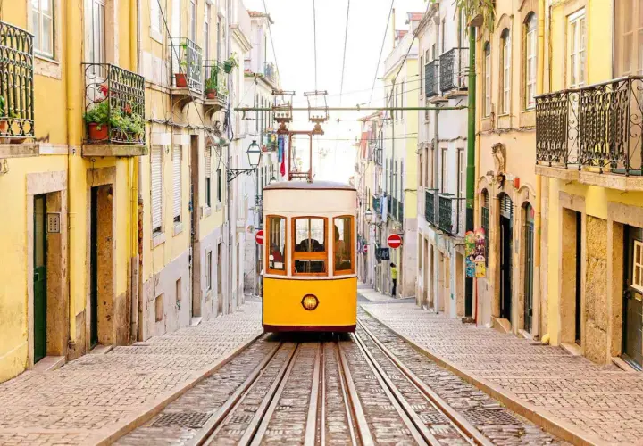A classic yellow tram ascends a steep, cobblestone street lined with colorful buildings, a perfect scene for one day in Lisbon.