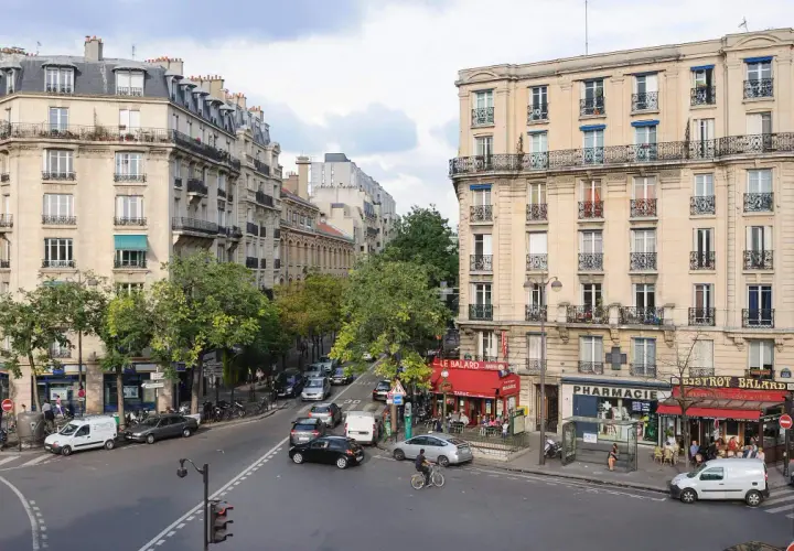 Ulica w 15 dzielnicy Paryża z kamienicami, kawiarnią i apteką. Ruch uliczny, piesi i rowerzysta.
